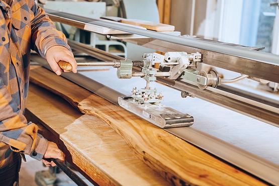 Eine Schleifmaschine wird bedient, die eine Holzplanke glattschleift.